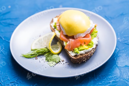 Preview: Sandwich with smoked salmon, egg and avocado on blue background. Concept for healthy nutrition