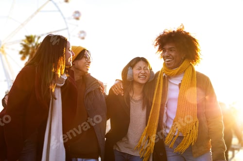 Preview: Group of friends laughing while embracing and walking together on sunny winter day in the city.