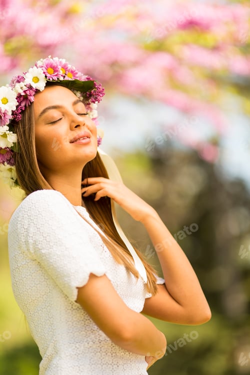 Preview: Young woman with flowers in her hair on sunny spring day