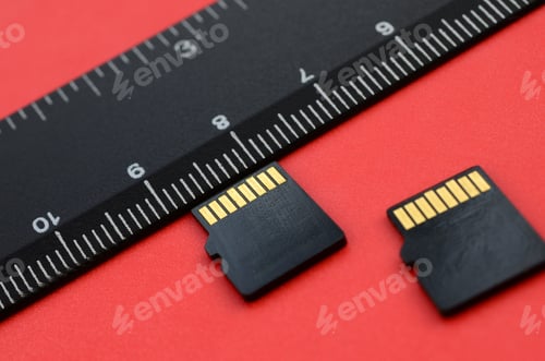 Preview: Two small micro SD memory cards lie on a red background next to a black ruler
