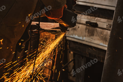 Preview: partial view of worker using circular saw with sparkles at factory