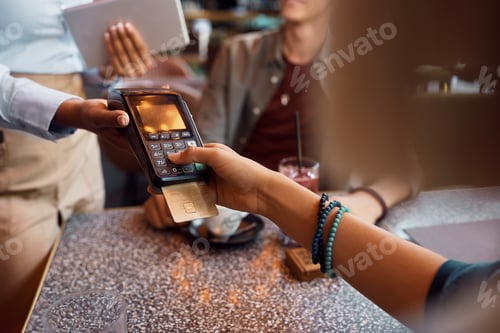 Preview: Close up of woman entering pin while paying with credit card in cafe.