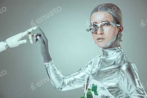 Preview: cyborg touching robotic arm and looking at camera isolated on grey, future technology concept