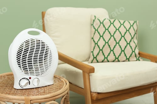 Preview: Electric fan heater on wicker table indoors. Space for text
