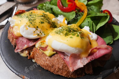 Preview: Delicious eggs benedict with ham and fresh green salad on display