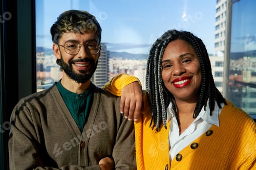 Preview: Two smiling business people posing together in modern office with city view