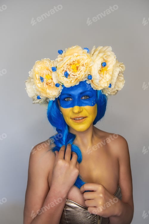 Preview: Creative close-up portrait of young happy Ukrainian patriotic woman with yellow blue face art wreath