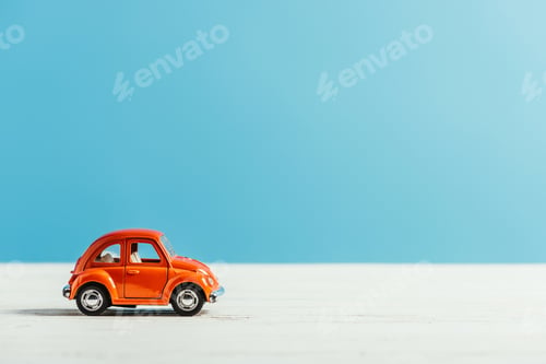 Preview: side view of toy red car riding on white surface on blue background