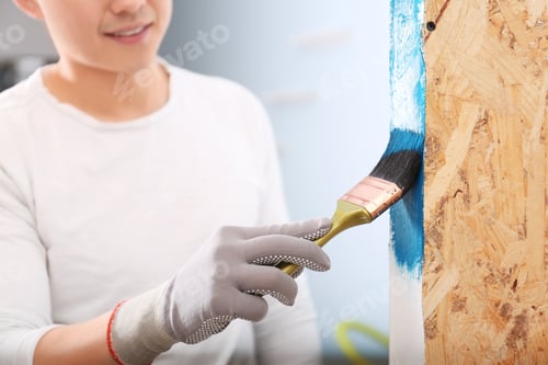 Preview: Male decorator painting wall with brush indoors
