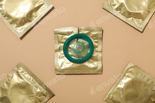 Preview: Condoms in a golden wrapper on a light background close-up