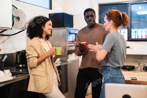 Preview: Multiracial coworkers enjoying coffee break in office kitchen