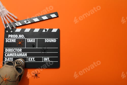 Preview: Clapperboard and Halloween decorations on orange background, space for text
