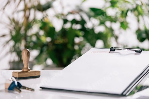 Preview: selective focus of keys, stamp and clipboard on white desk, mortgage concept