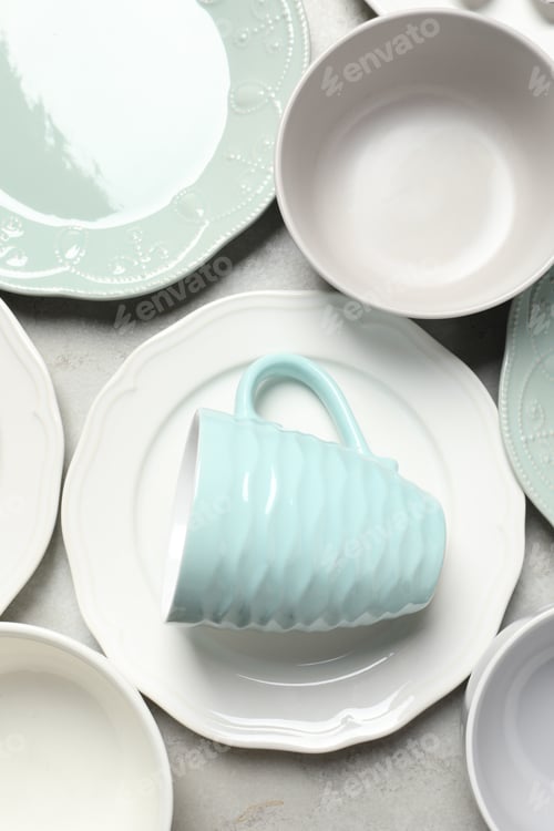 Preview: Beautiful ceramic dishware and cup on light grey table, flat lay