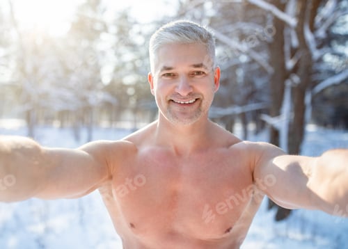 Preview: Positive senior man with bare chest taking selfie at snowy winter forest. Acclimation concept