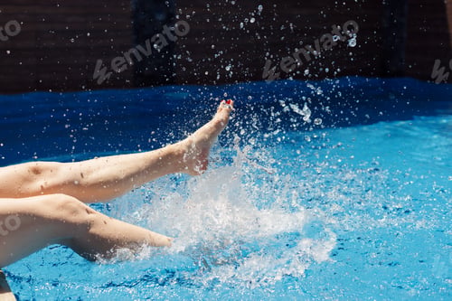 Preview: Woman legs making water splashes in the pool. Summer time