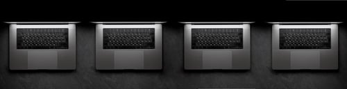 Preview: Row of identical laptops in monochrome light for corporate teams. Digital device fleet.