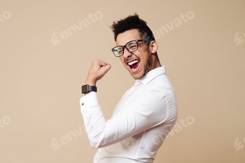 Preview: Afro young man celebrating victory on beige background