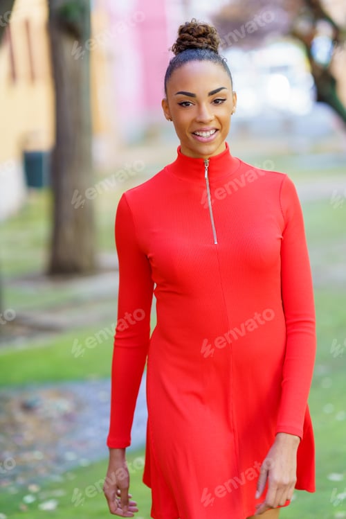 Preview: Smiling black woman in red dress walking down the street