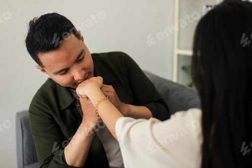 Preview: Man kissing woman's hand in a cozy indoor apartment setting, highlighting a tender