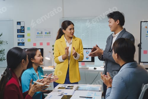 Preview: Asian businesspeople clapping hands during a meeting in the office, celebrating the success of achie
