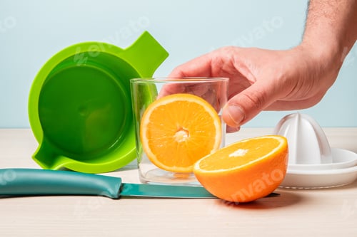 Preview: Closeup shot of a hand grabbing a glass with freshly cut oranges