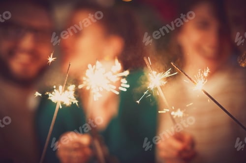Preview: Group of friends with sparklers celebrating Christmas at home
