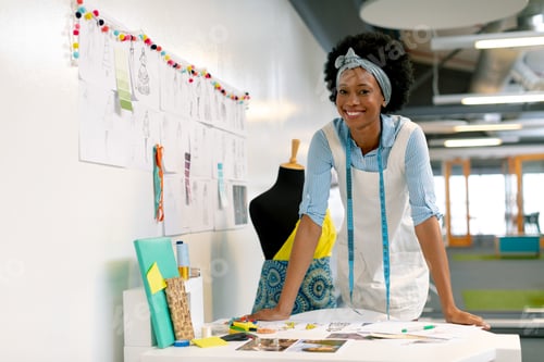 Preview: Front view of happy African american female graphic designer leaning on table in office