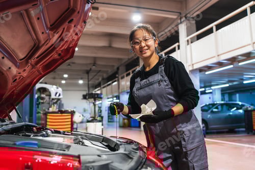 Preview: Female chinese mechanic checking oil level of car in repair shop