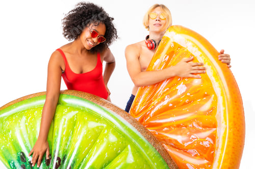 Preview: happy couple european guy and african girl in swimsuits with sunglasses and headphones go swimming