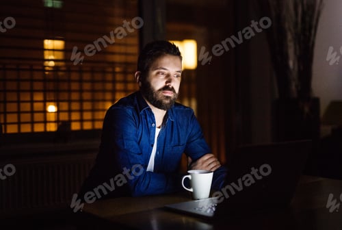 Preview: A man working on a laptop at home at night.