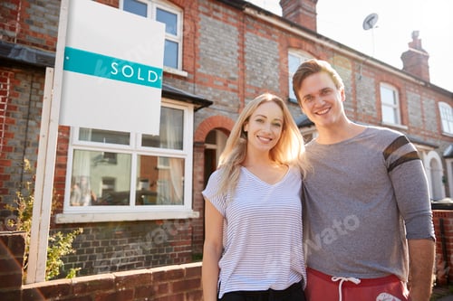 Preview: Portrait Of Excited Couple Standing Outside New Home With Sold Sign