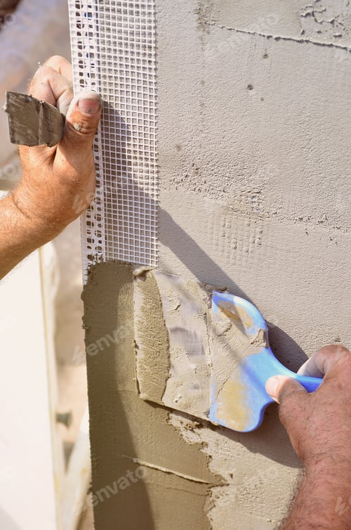 Preview: Hands of an old manual worker with wall plastering tools renovating house