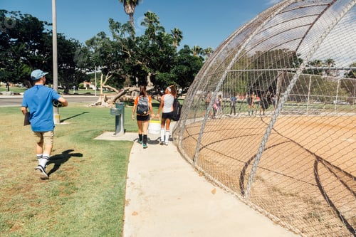 Preview: Rear view of teacher and schoolgirl soccer players walking to practice on school sports field