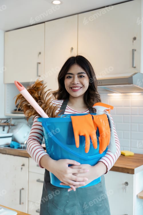 Preview: Smiling Cleaning Service Professional Holding Cleaning Supplies in a Modern Kitchen Setting