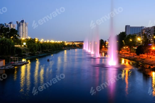 Preview: Evening night city landscape. Beautiful bright colored fountains on the river. Neon lights.