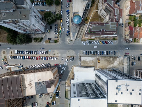 Preview: Aerial view of an urban neighborhood with high-rise buildings, parked cars, and intersecting streets