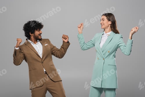 Preview: Excited interracial event hosts in formal wear showing yes gesture and looking at each other during
