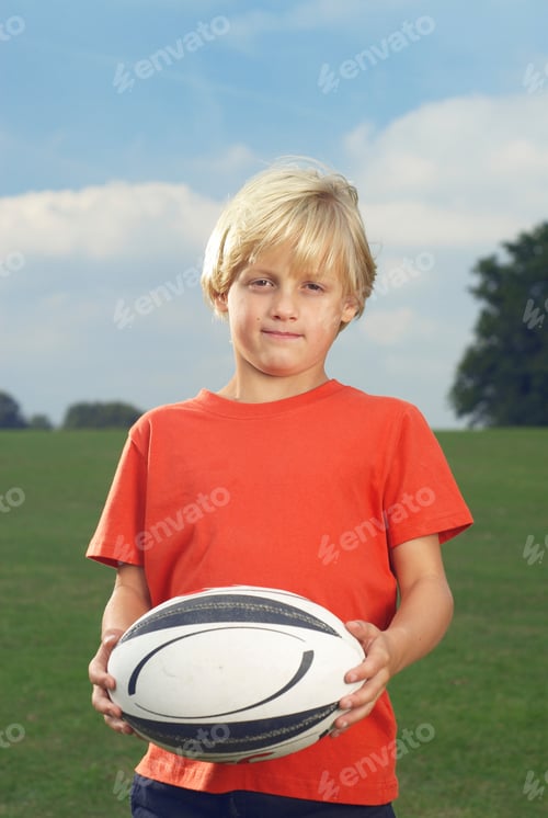 Preview: boy holding rugby ball in filed