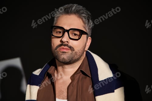 Preview: Stylish man in glasses showcases elegant fashion in a modern studio setting