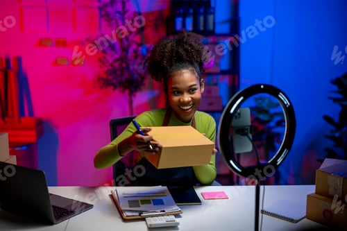 Preview: A woman is sitting at a desk with a box in front of her