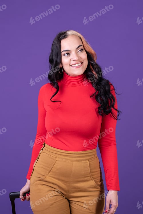 Preview: Happy woman traveler holding her suitcase while walking against purple background.