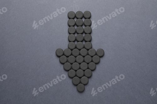 Preview: Arrow made of activated charcoal pills on grey background, flat lay. Potent sorbent