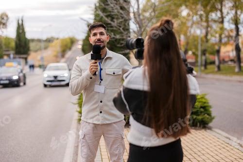 Preview: Male reporter speaking into microphone with camerawoman filming