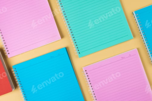 Preview: Composition of diverse colorful notebooks lying on yellow surface