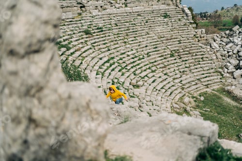 Preview: School boy kid in yellow hoodie and blue jeans exploring remains of ancient arena stone coliseum