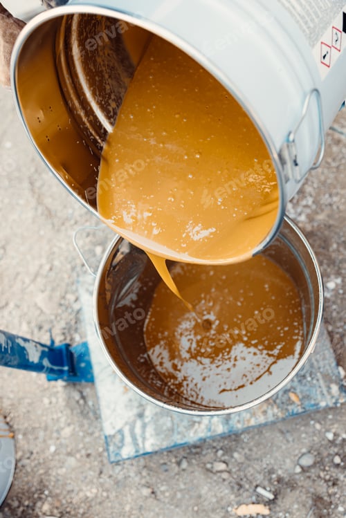 Preview: Pouring yellow resin from the metal bucket for preparing floor