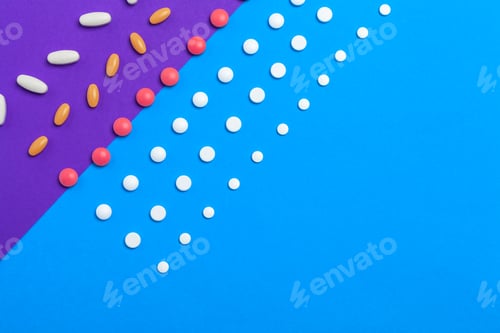 Preview: A pile of multicolored pills on blue background. Top view.