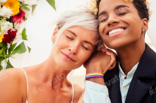 Preview: african american female groom in black suit and happy caucasian blonde bride