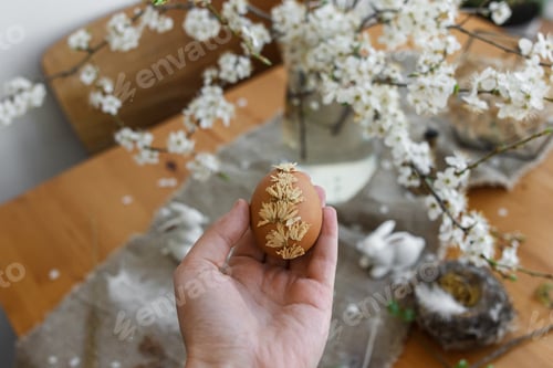 Preview: Decorated Egg Held near White Flowers and Bunnies